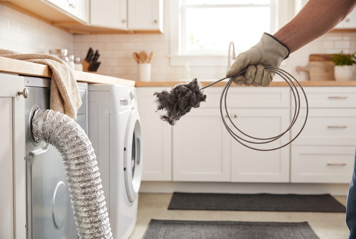 Lint being pulled from a silver dryer vent duct in a bright San Antonio laundry room